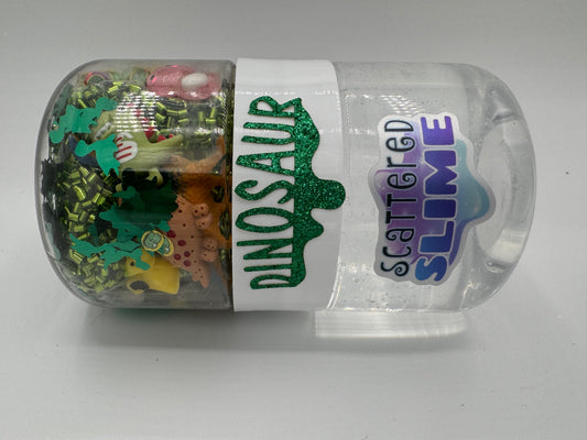 Container of dinosaur-themed scattered slime with colorful contents on a gray background