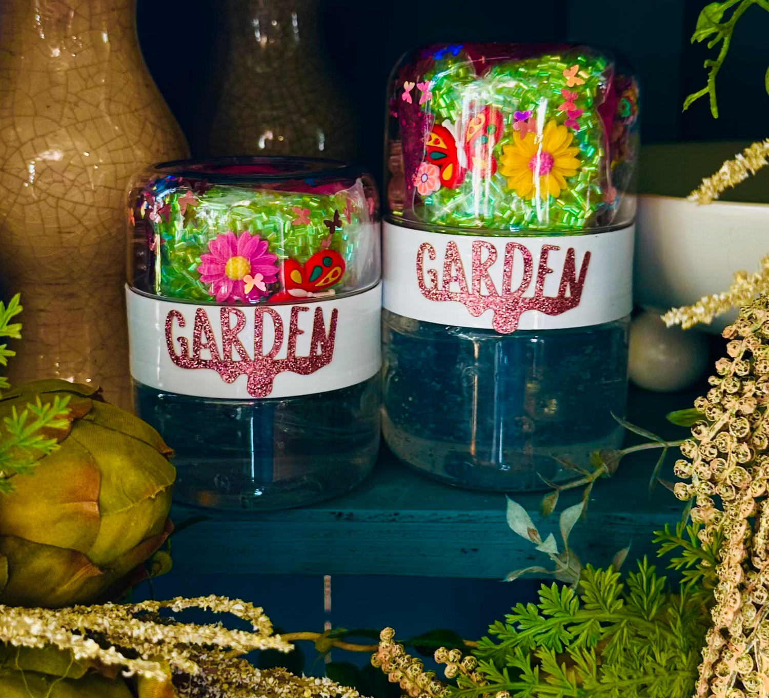 Decorative slime jars with floral designs and 'Garden' text on the jars with plants.
