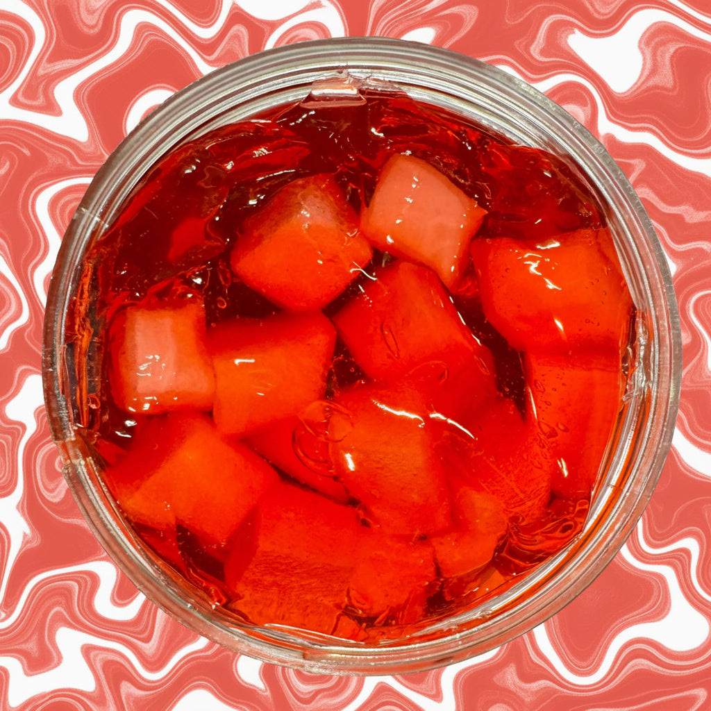 Clear container with red jelly-like cubes on a metallic surface
